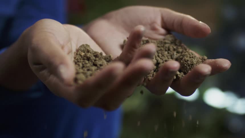 A woman drops dirt from her hands