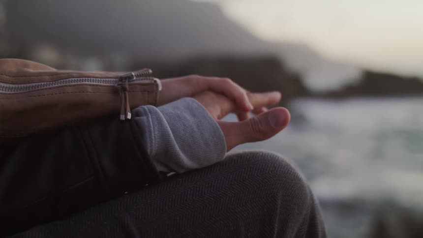 A man and woman hold hands on a beach at sunset