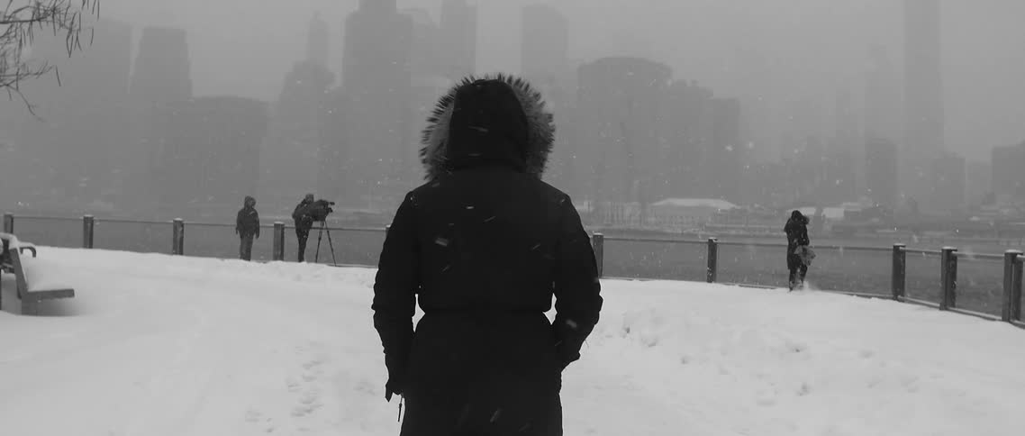A woman walking towards an urban coastline in the snow