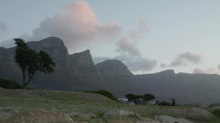 A couple are walking along a hillside at dusk on a windy day
