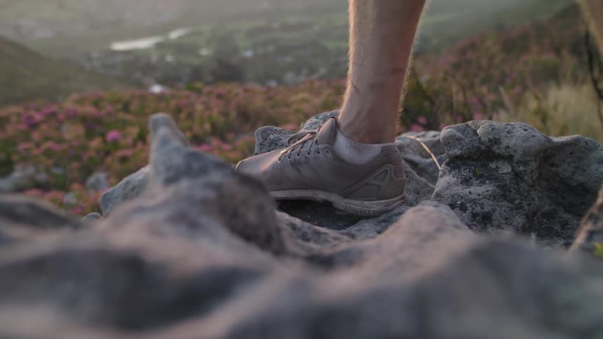 A man stands atop rocks on the hill
