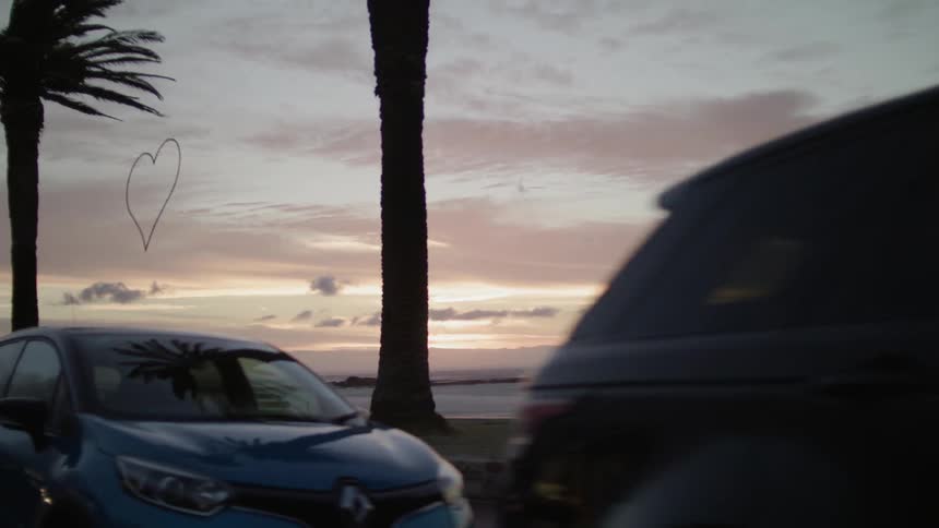 Cars are parked along the shore at sunset