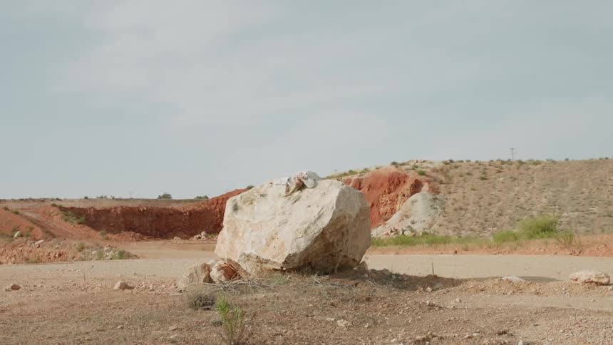 Woman is laying on large boulder in the sun on windy day