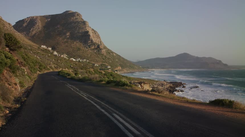 The waves crash against the shore close to the road