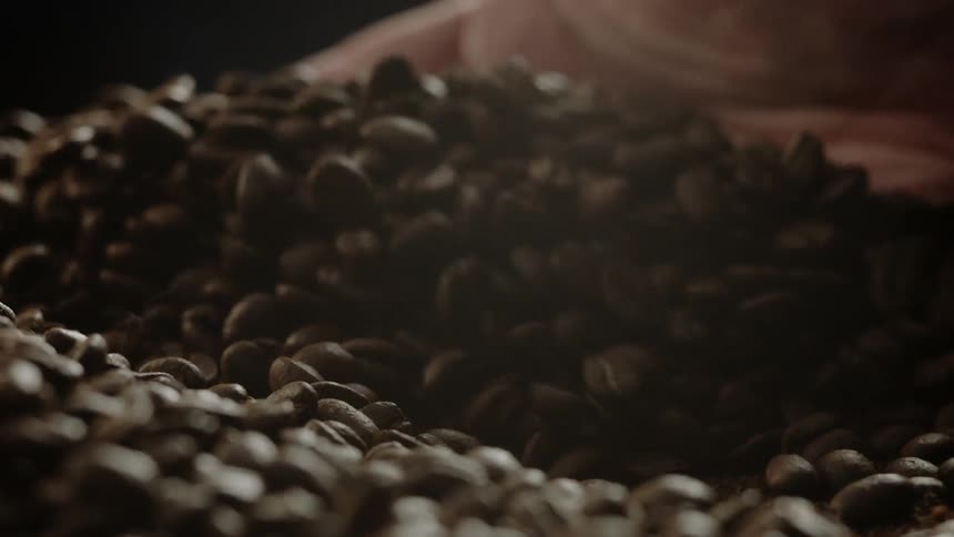 A person runs their hand over coffee beans