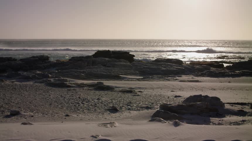 Ocean waves wash ashore a beach at sunset
