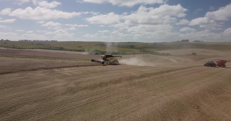 Farm equipment kicks up dust as it clears a field