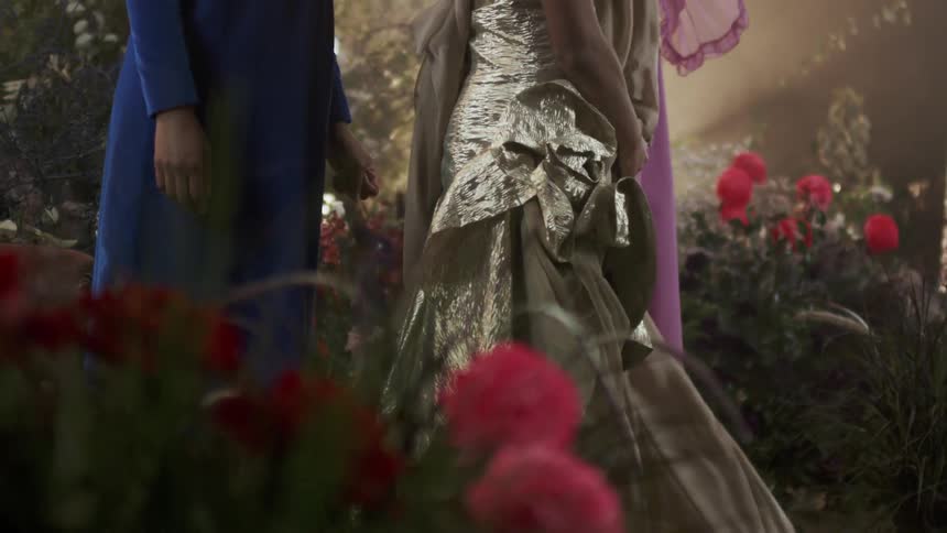 Women in dresses stand on a set together