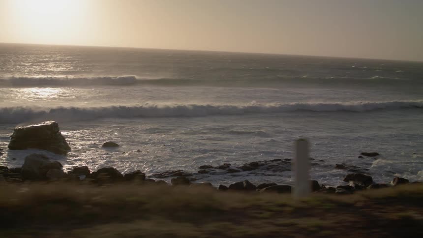 The rough waves crash against the beach at sunset