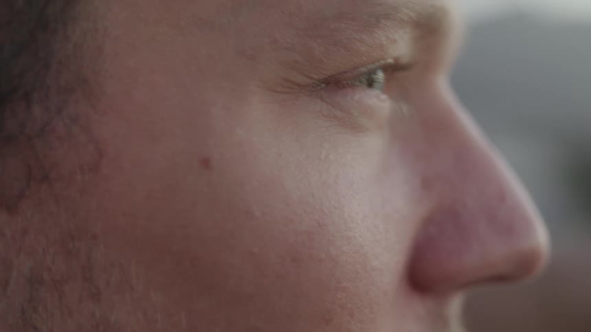 A man blinks and looks around outside