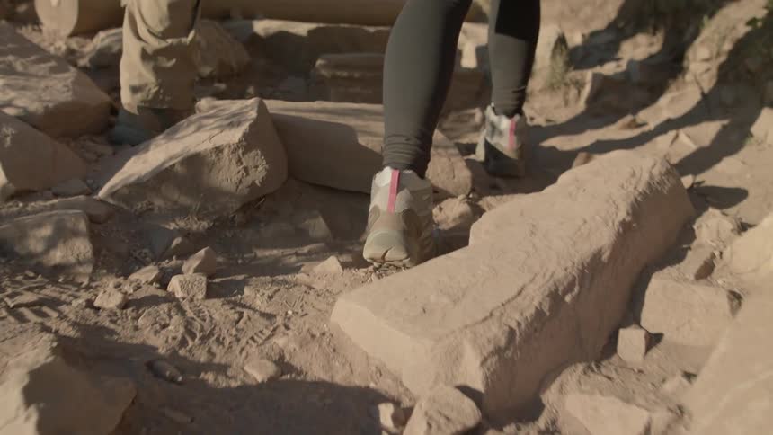 Two people walk over rocks and dirt