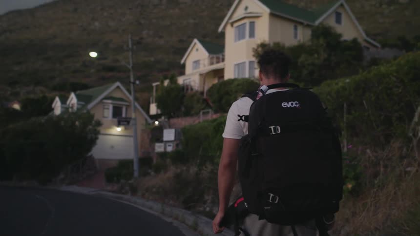 Man wearing a backpack walks down a street at night