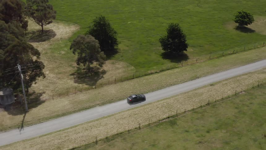 Car drives down a country road in flat land
