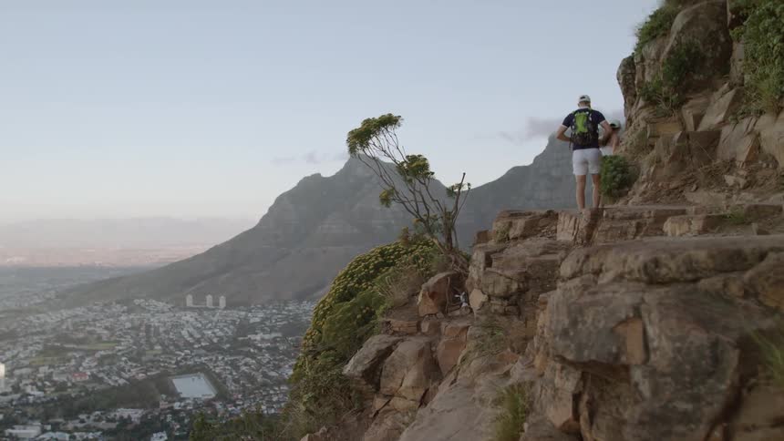 A couple walk on the rocks on a cliff by the town