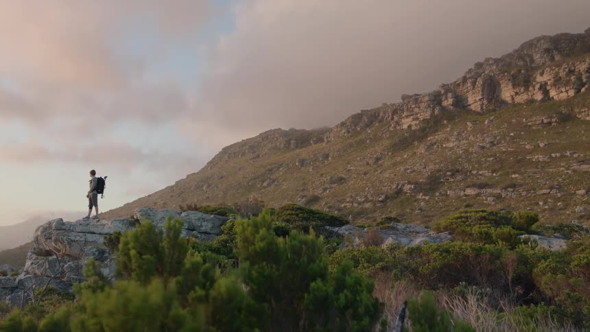The man stands on the edge of a cliff on a windy day