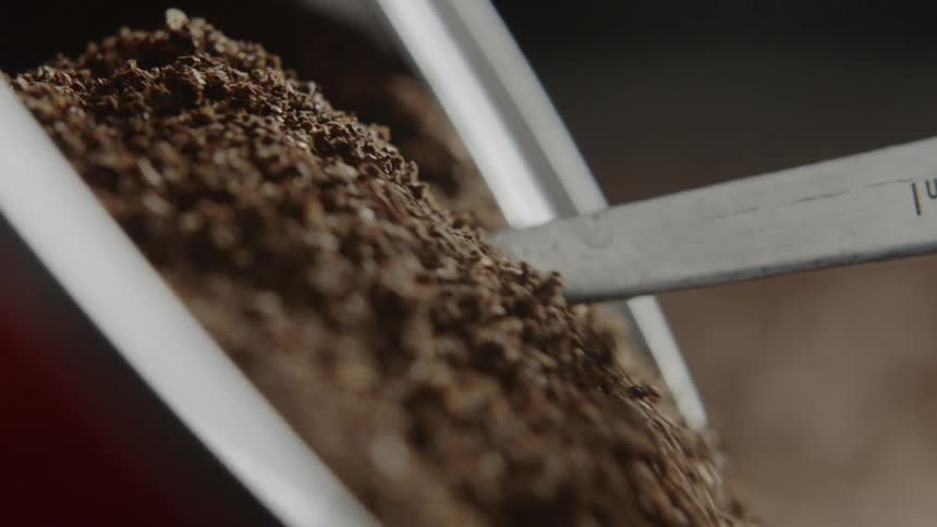 A silver scoop is filled with coffee grounds