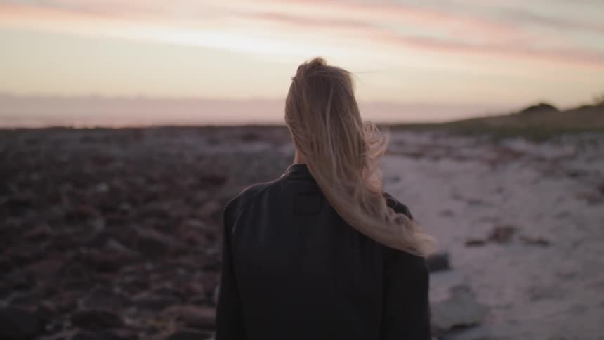 A woman walks on the beach on a windy day