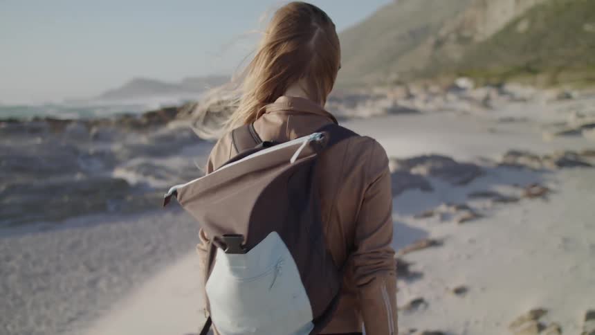 A woman walks on the windy beach