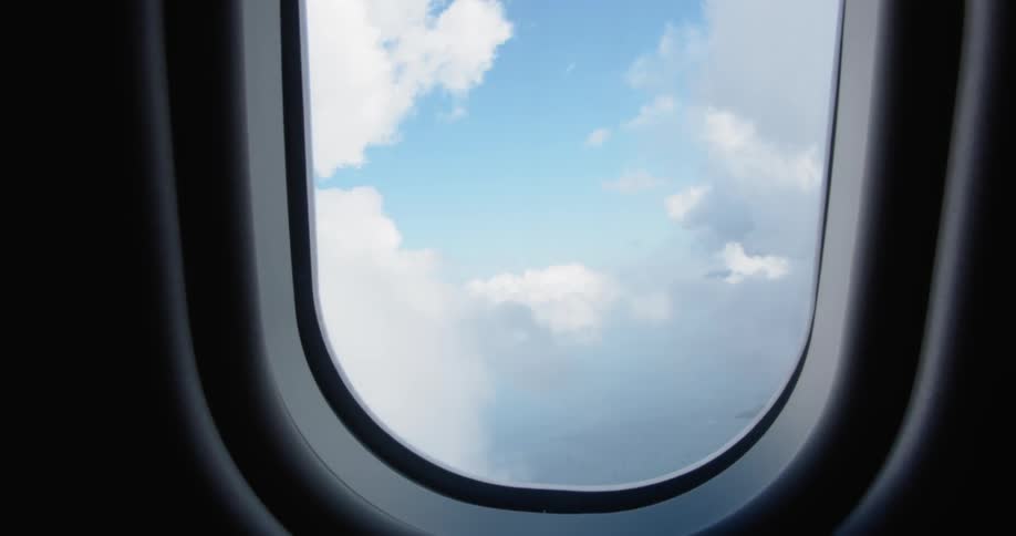 Clouds are billowing and drifting in the sky outside an airplane during the day