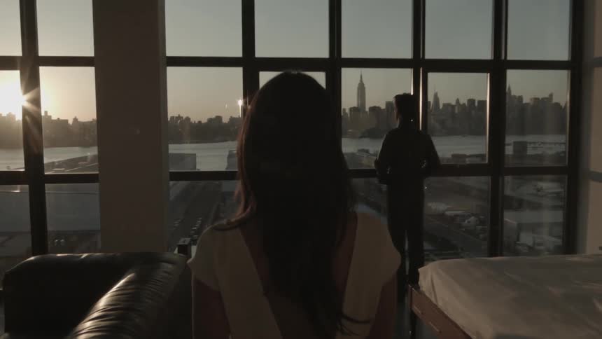 Woman walking over to a man standing by a window
