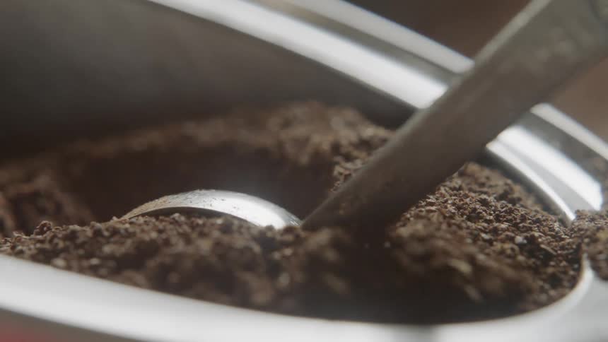 Coffee grounds are scooped from a container