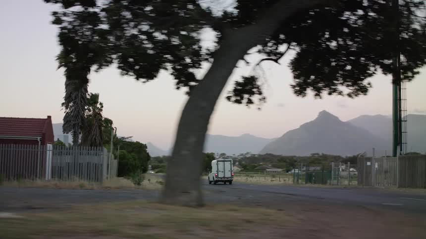 A car drives on a town street at sunset