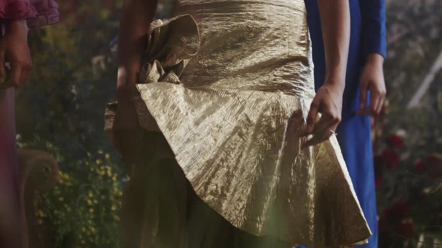 A woman stands wrapped in a gold dress