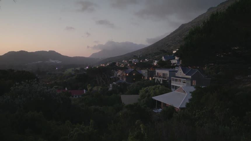 Buildings sit near the mountain under the cloudy sky