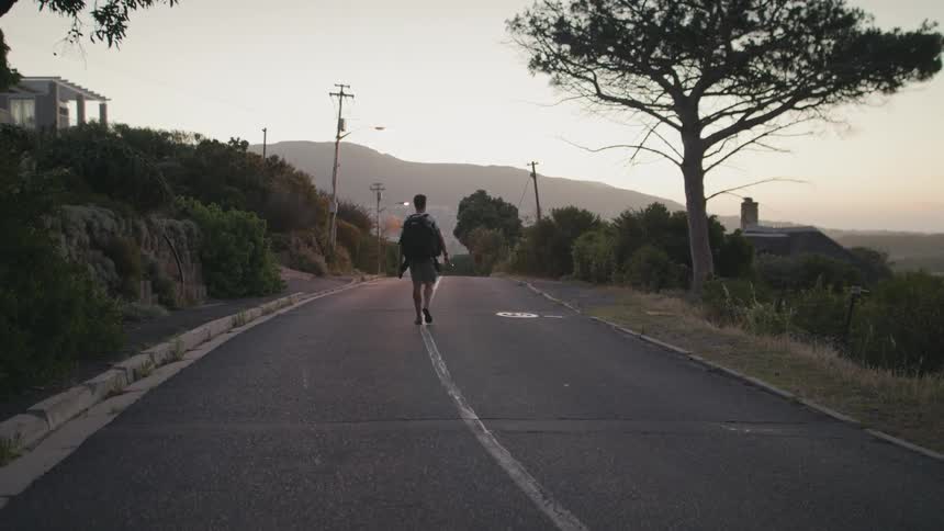 Man walks on a rural road at sunset
