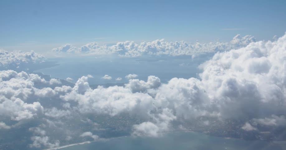 Billowing clouds hover in the sky above a coastal community in daylight