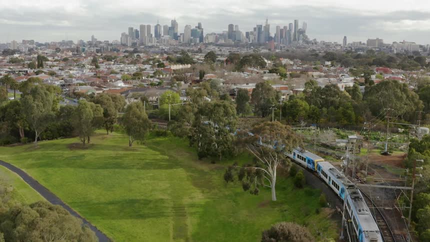 Train is traveling on outskirts of city on cloudy day