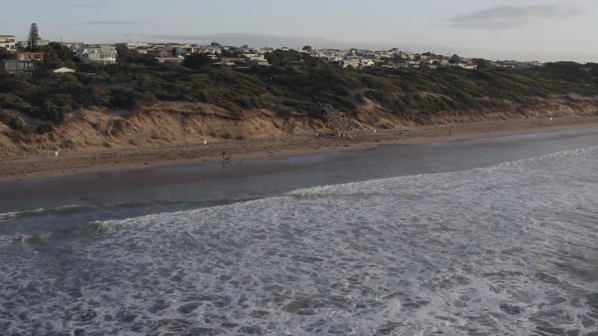 Waves roll into shore under a blue sky