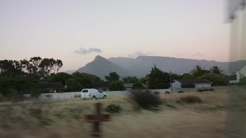 White truck drives down a country road toward houses at sunset