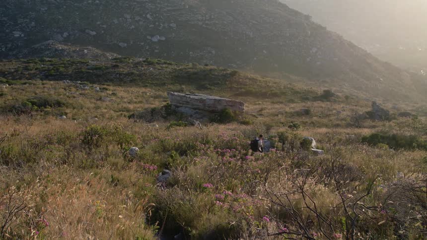 A man is hiking among the scrub brush in a natural setting during the day