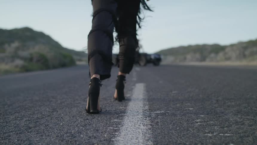 Woman walks towards a man and a vehicle under a blue sky
