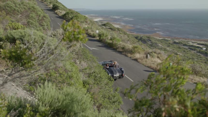 A convertible drives on the coastal road