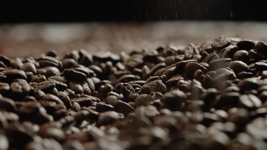Coffee beans and grounds pour down into a large pile