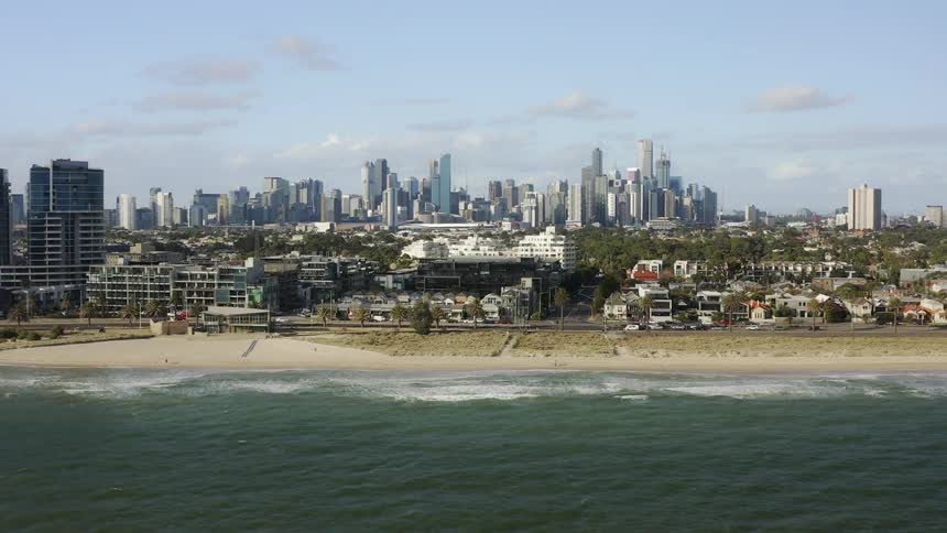 Ocean waves come to shore as traffic moves along the coastal city road