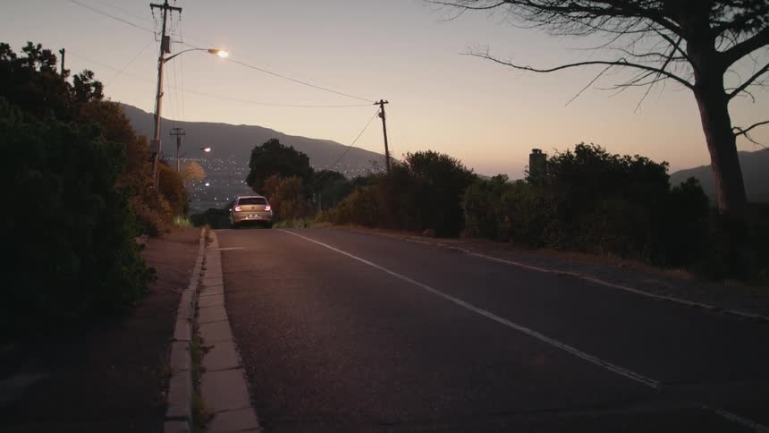 Vehicle drives down a country road at sunset