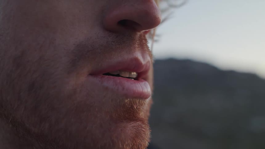 Wind blows through a man's hair in mountains at sunset