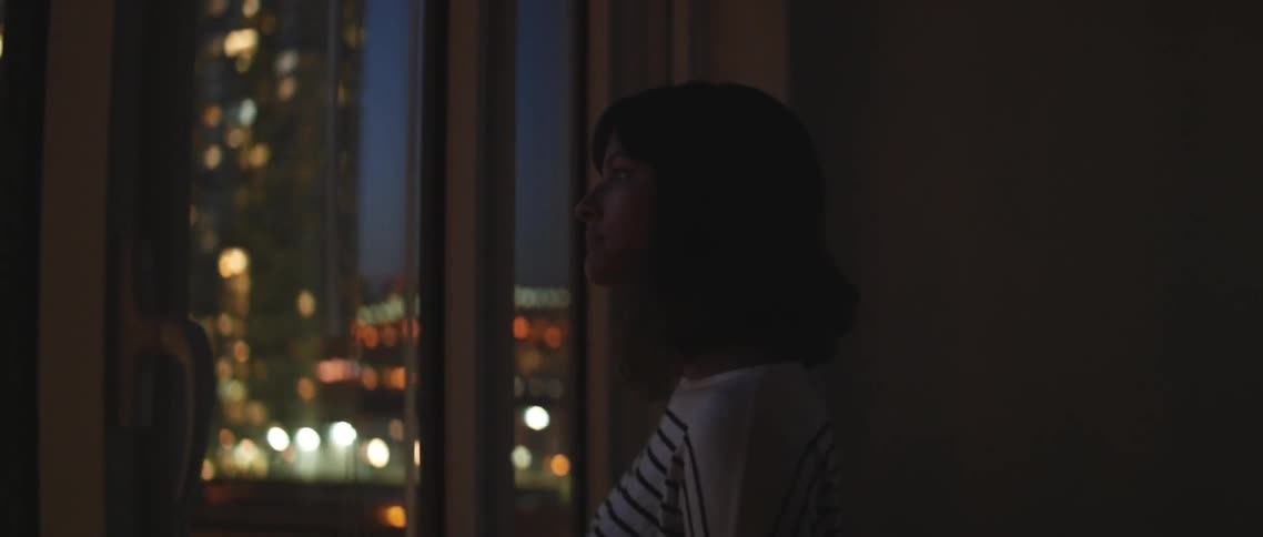 Woman walking through a dark room towards a window