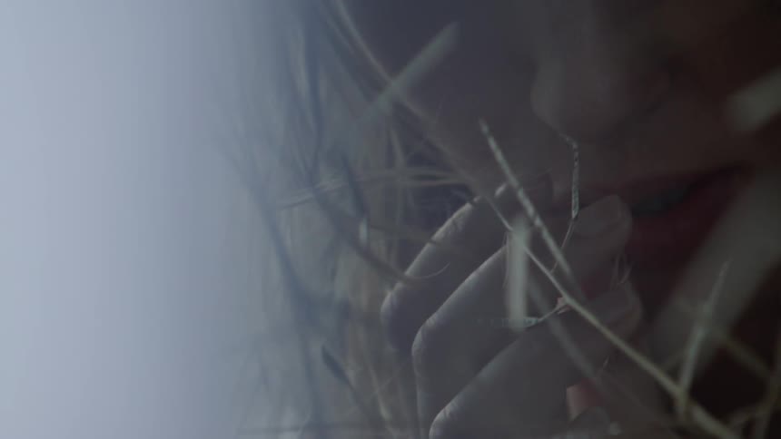 A woman touches some grass and smells it