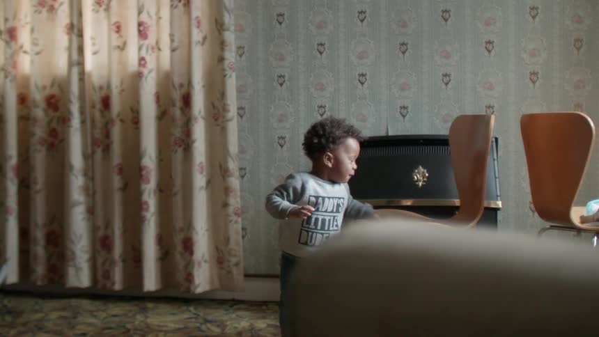 Toddler boy stands next to a chair