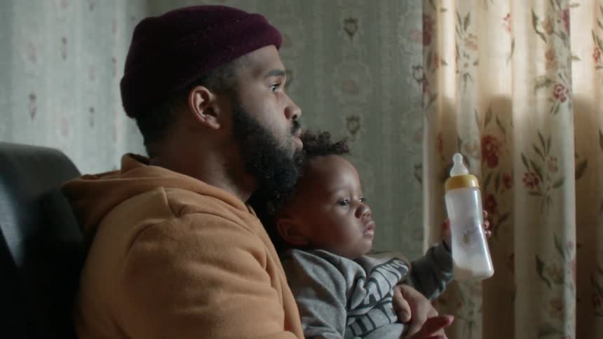 Man holds a baby drinking a bottle