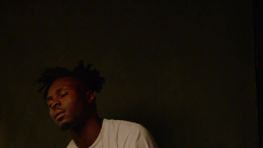 Man sways back and forth with his eyes closed in a dim room