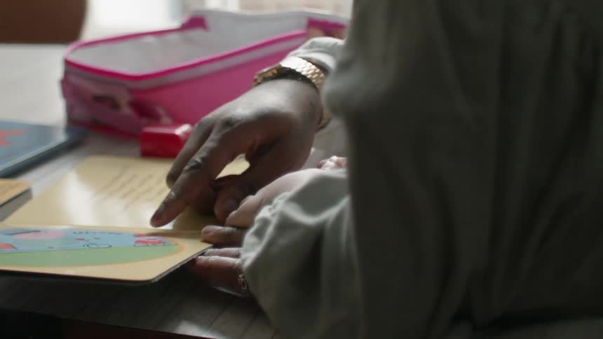 Woman turns the pages of a story book as a child watches