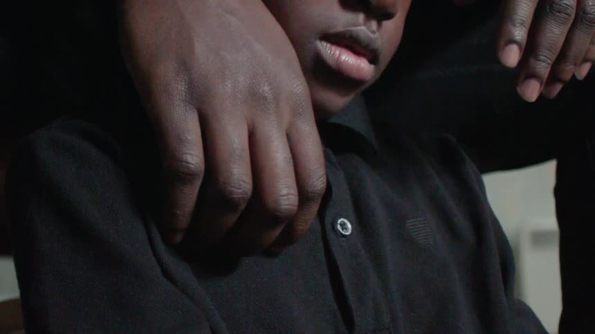Person's hands on a child's shoulders