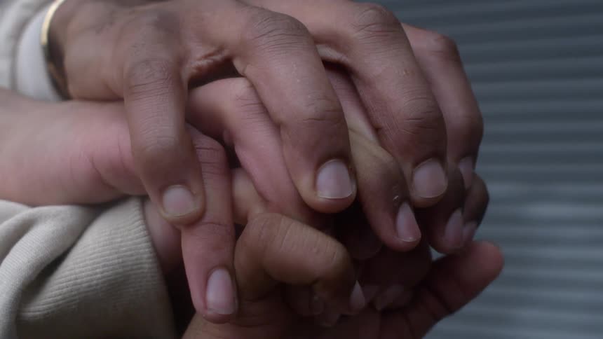 People clasp their hands one on top of another