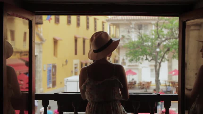 A woman looks out at a city from a balcony