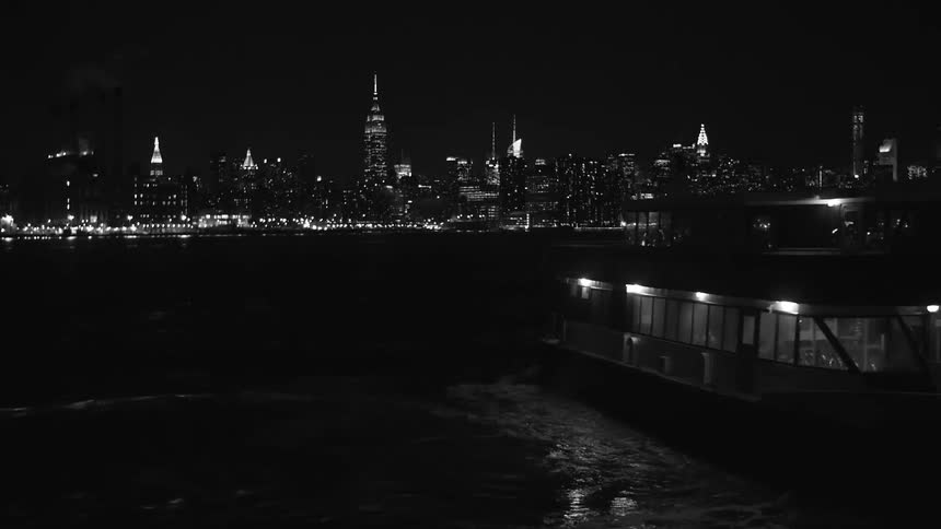 A boat headed towards a city at night